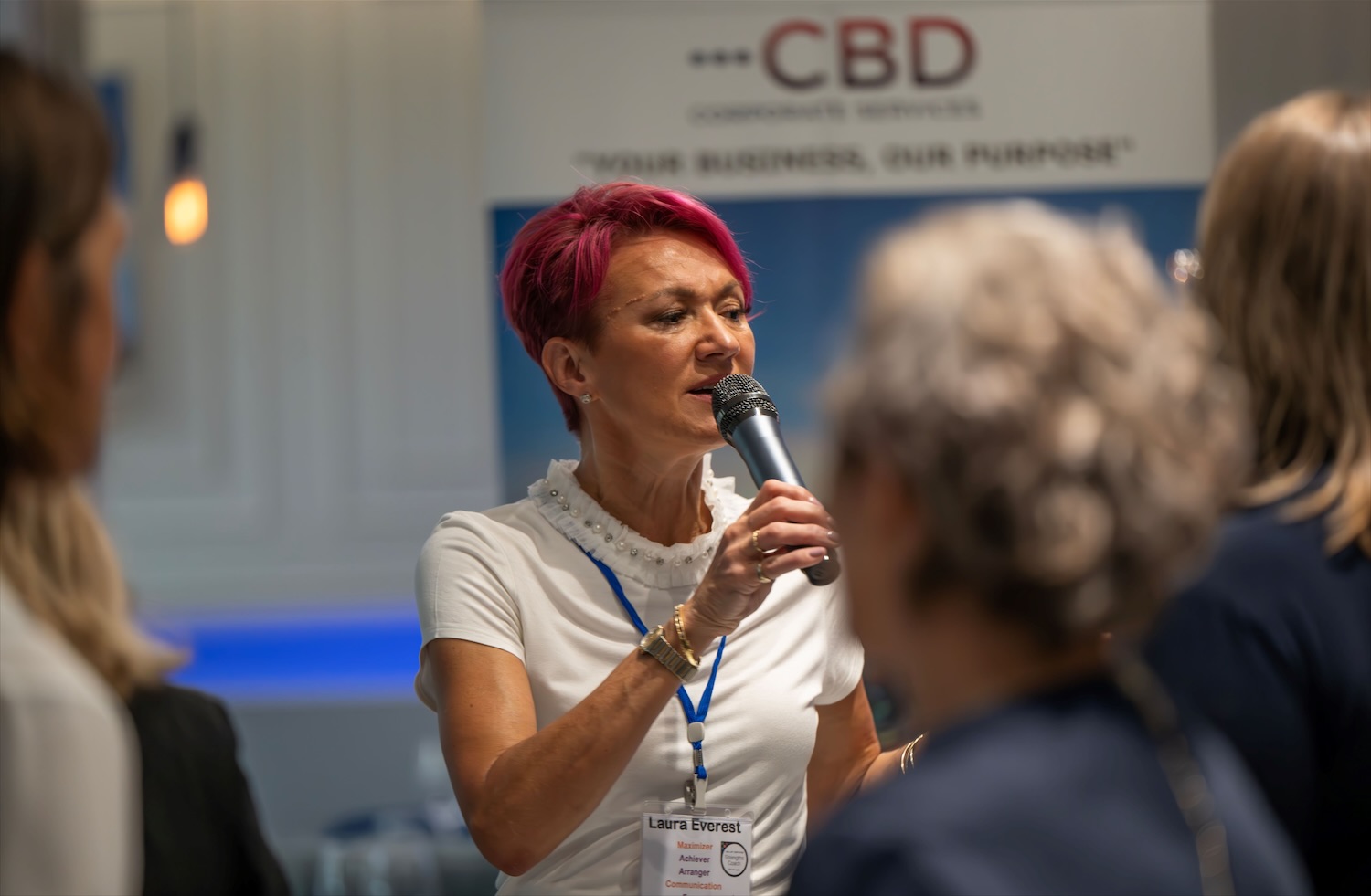 Laura Everest speaking with a microphone at a corporate event